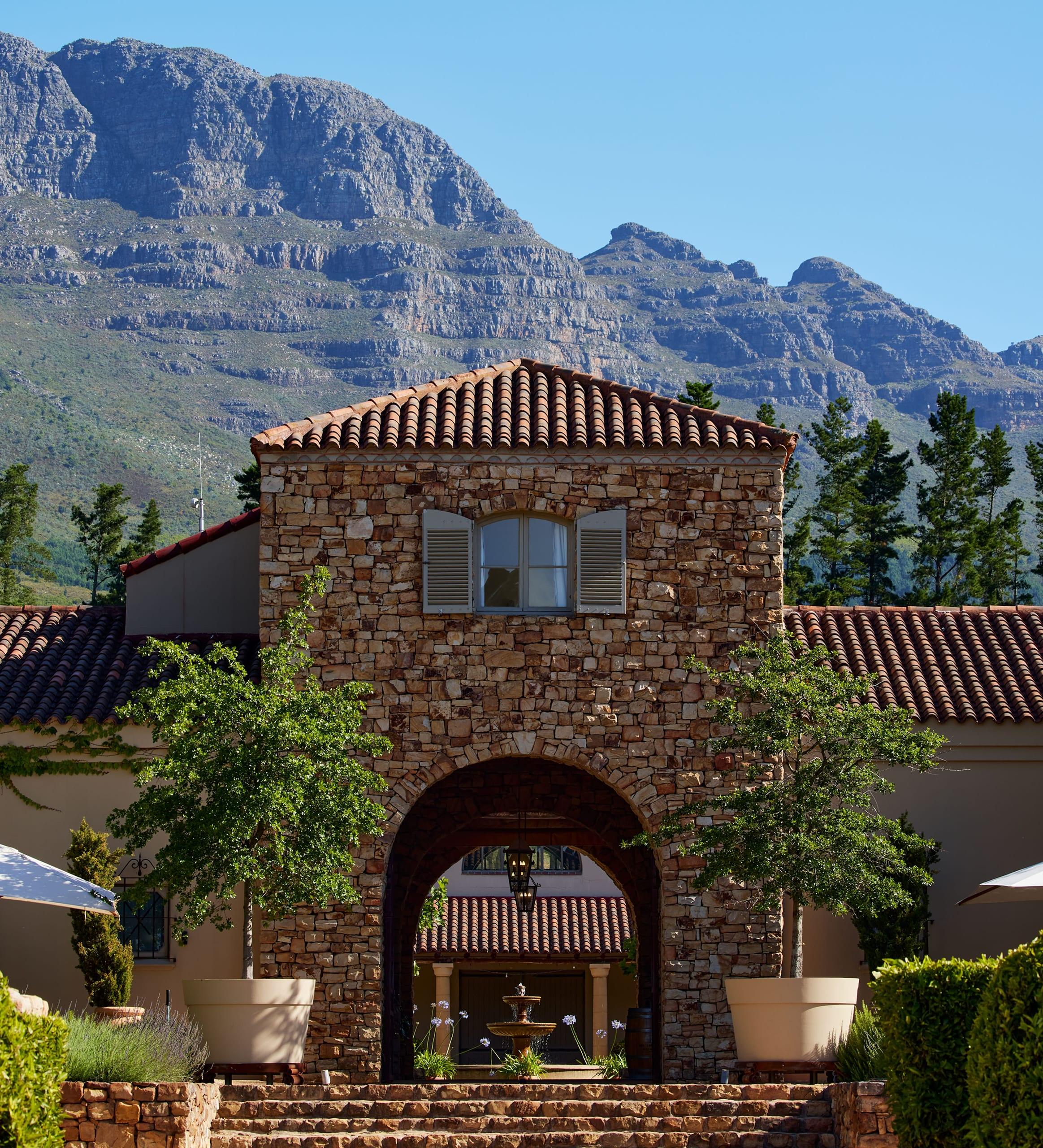 A stone villa with a mountain backdrop