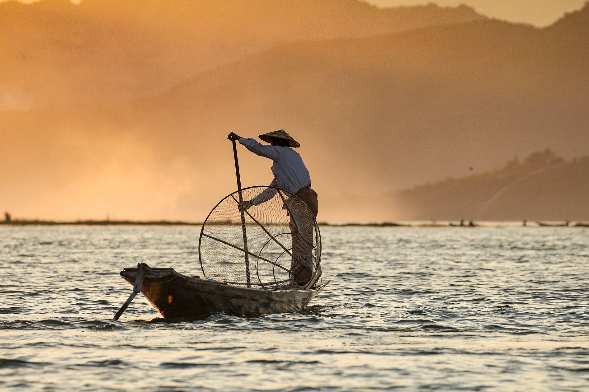 Fisherman on boat at sunset
